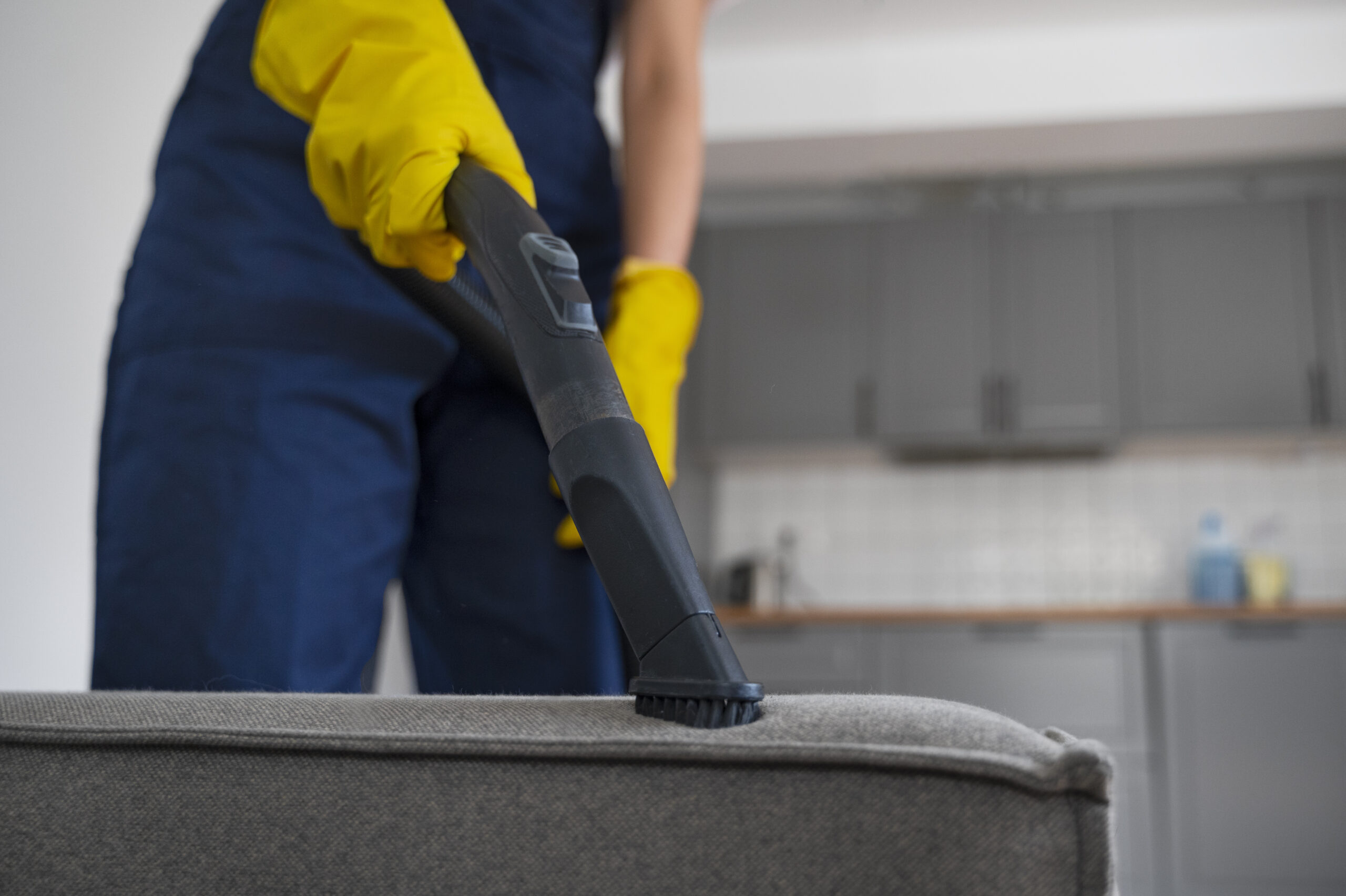 Vacuuming an upholstered sofa for spring furniture cleaning