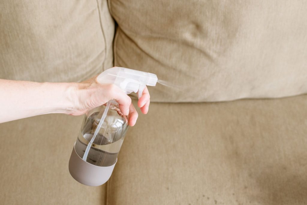 spraying baking soda and vinegar deodorizer for a furniture refresh